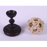 A Chinese carved ivory nesting ball, 2 1/4" dia, on turned hardwood stand (damages to ball)