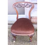 A Victorian carved rosewood low seat nursing chair, on cabriole supports