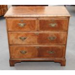 A figured walnut and feather banded chest of two short and two long drawers with brass handles, on