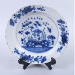 An English delft blue and white plate, decorated with insects, root and plant, 10" dia (rim chips)