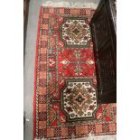 A rug decorated with two elephant feet on a red ground with multi-border stripes, 53" x 33" approx