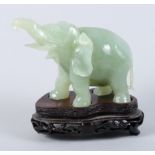 A carved jade elephant, on carved wooden stand, 4 1/4" high (damages), and a pale celadon carved