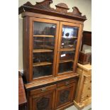 A late Victorian carved walnut bookcase, the upper section enclosed glazed doors over two drawers