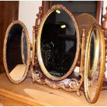 A gilt framed oval triptych mirror, 22" high