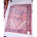 A Middle Eastern rug with central medallion, geometric and floral design on a terracotta ground