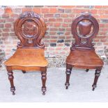 Two 19th century carved mahogany pierced back hall chairs with panel seats, on turned supports