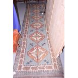 A Kazak design runner with six diamond lozenges in shades of fawn and natural on a light blue