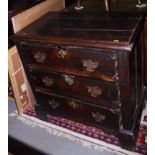 A largely late 17th century oak chest of three drawers with later pierced back plates and brass bail