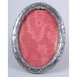 A late Victorian oval silver photograph frame with embossed decoration