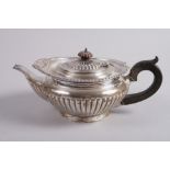 A compressed melon-shaped silver teapot with half reeded decoration and ebonised handle and