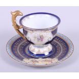 A Vienna cabinet cup and saucer, decorated with floral and figure panels, on a blue ground with gilt