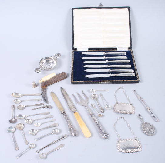 A selection of silver items, including condiment spoons, a tea strainer, two decanter labels, a