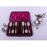A silver cream jug with scroll handle, on shell feet, a boxed set of six silver teaspoons and a pair