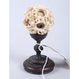 A Chinese carved ivory nesting ball, 2 1/4" dia, on turned hardwood stand (damages to ball)