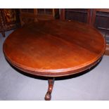 A Victorian walnut circular tilt top dining table, on turned column and carved tripod splay support,