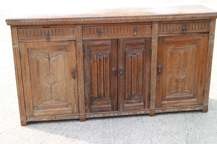 A carved oak side cupboard, fitted three drawers over cupboards enclosed linen fold doors, 63" wide