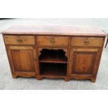 An oak sideboard with three drawers over central recess and two cupboards, on bracket feet, 60"