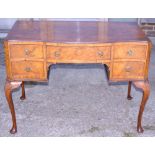 A figured walnut serpentine front writing table, fitted four small and one long drawer, on shell