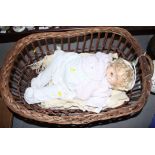 A composition petite doll with sleeping eyes, in a wicker pram