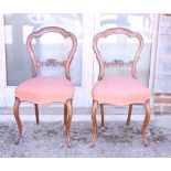 A pair of Victorian carved walnut loop back side chairs with stuffed over seats, on cabriole