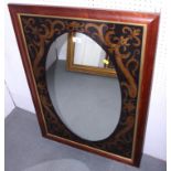 A wall mirror with decorated plate and oval centre, 28" x 16 1/2", in polished as mahogany frame