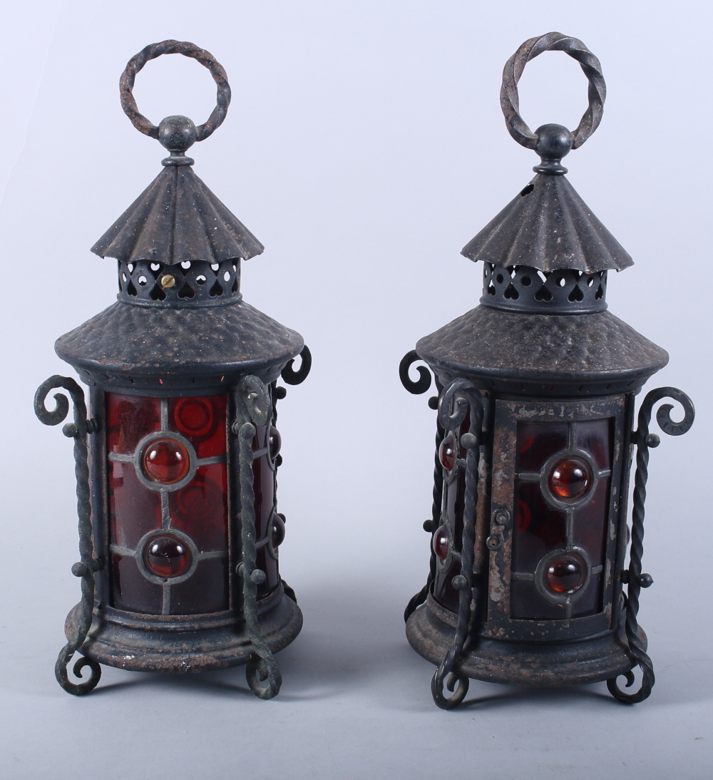 A pair of wrought iron lanterns with red glass windows