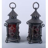 A pair of wrought iron lanterns with red glass windows