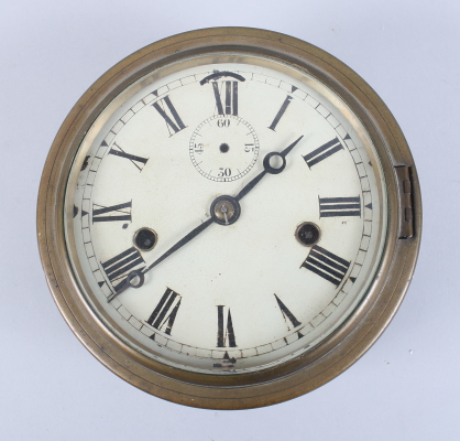 A metal cased wall clock with brass cover, white enamel dial and Roman numerals