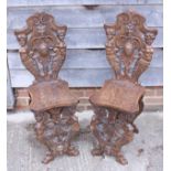A pair of Italian Renaissance design carved walnut hall chairs
