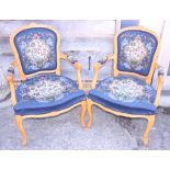 A pair of Louis XVI design polished as walnut open armchairs with needlework seat and back panels,