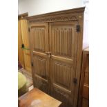 A 1920s limed oak wardrobe enclosed two linen-fold panelled doors, on stile supports, 42" wide