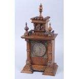 An early 20th century oak mantel clock with brass filigree embellishments, lion heads and studded