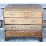 A late Georgian oak chest of four graduated long drawers with brass bail handles, on bracket feet,