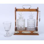 An oak cased two-decanter Tantalus with silver plated mounts 10" wide x 11" high (damages to