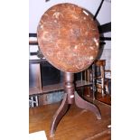 An early 20th century oak tilt top circular table, on three splayed supports (heavy staining to