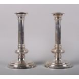 A pair of silver cylindrical candlesticks with filled bases, 9 1/2" high