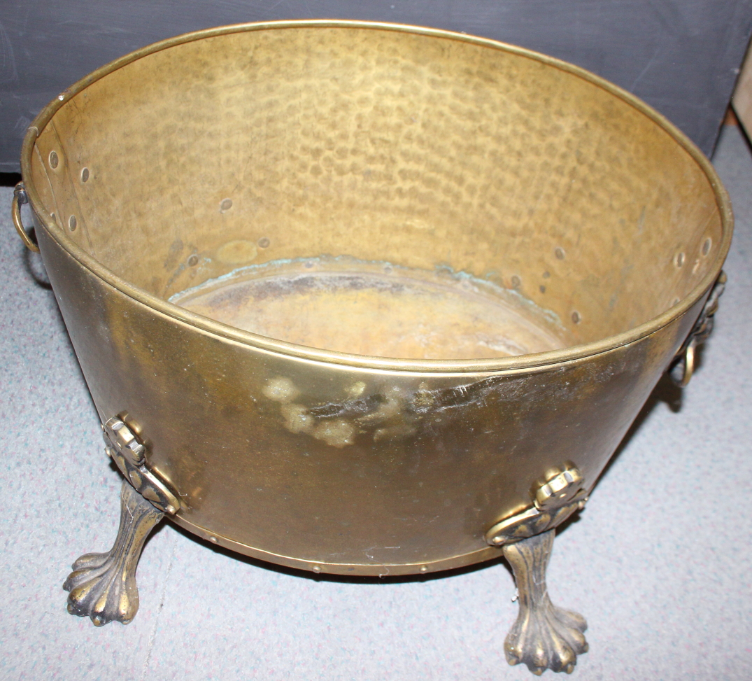 A brass oval two-handle log bin with lion paw feet, 17" wide