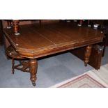 An Edwardian oak extending dining table with two extra leaves, on reeded supports, 15" x 102" when