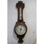A late 19th century carved oak cased aneroid barometer and thermometer