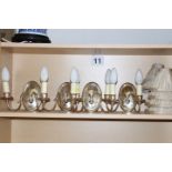 A set of four silver plated two-branch wall lights of Adam design with oval backs and shades and a