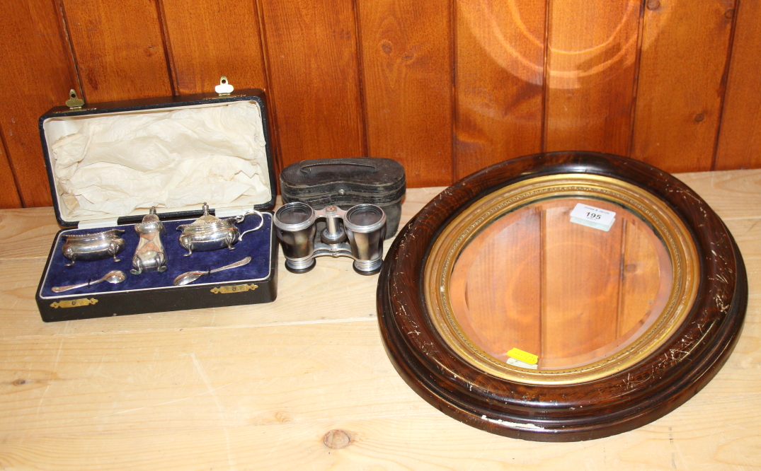 An oval wall mirror, a silver plated three-piece cruet and a pair of opera glasses