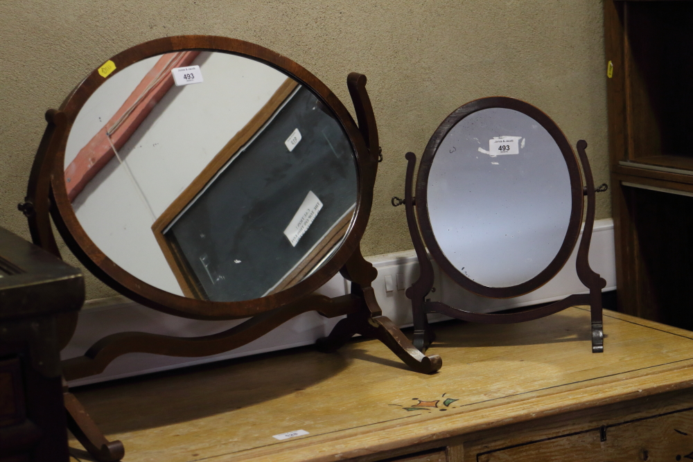 Two mahogany swing frame toilet mirrors on skeleton frames, and two wooden magazine racks