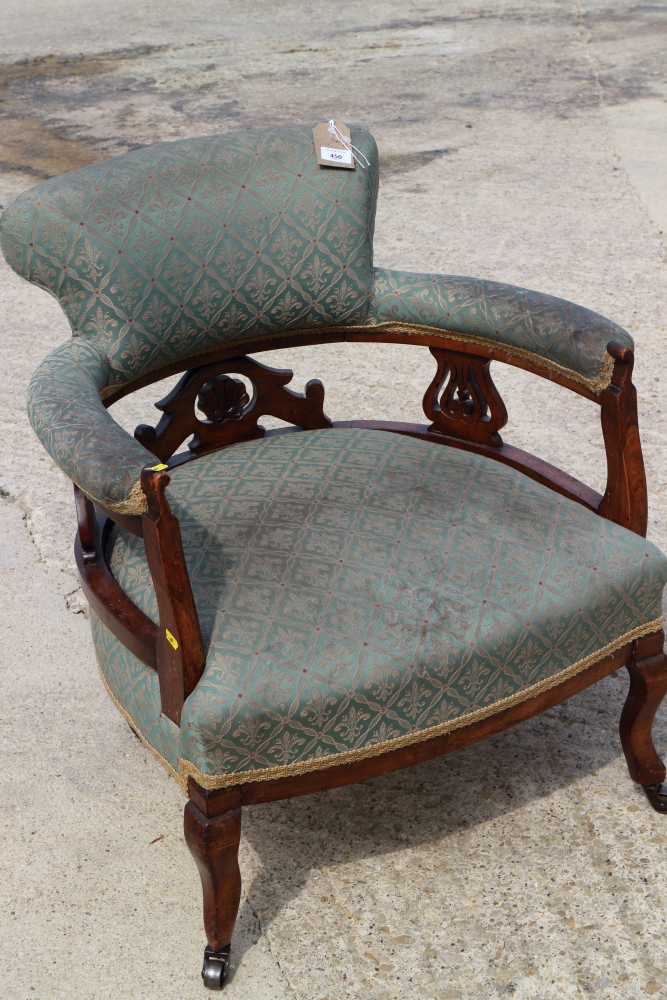 An Edwardian tub-shape elbow chair, upholstered in a fleur-de-lys pattern fabric, on cabriole