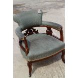 An Edwardian tub-shape elbow chair, upholstered in a fleur-de-lys pattern fabric, on cabriole