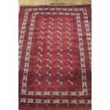 An Afghan Bokhara rug with forty-eight guls of traditional design on a red ground, 56" x 73" approx