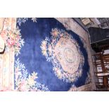 A Chinese carpet with central ivory floral medallion on a dark blue ground with matching border,