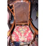 A walnut framed cane back low armchair, upholstered in a floral pattern fabric