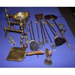 A pair of twisted brass fire iron rests, fire implements, a cream skimmer, a brass scoop, etc