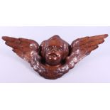 A carved wooden wall decoration of a winged cherub's head, 25" across