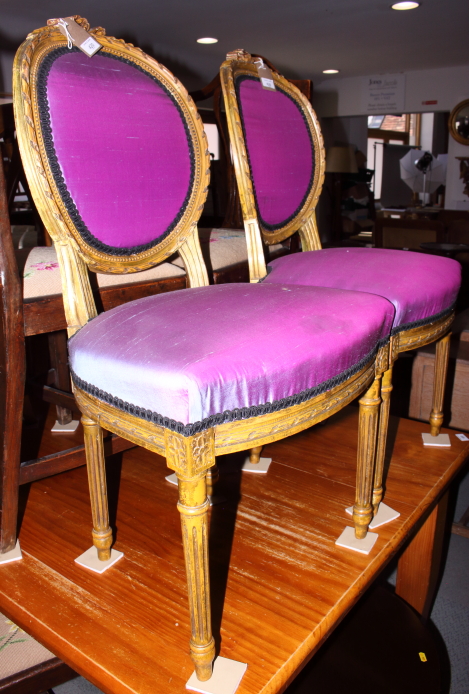 A pair of Louis XVI design giltwood salon chairs, upholstered in a purple fabric